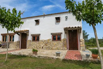 an exterior view of a white house with a stone wall at Masia Pou de la Vinya in Sitges