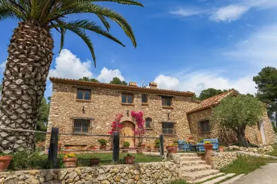 an old stone house with a palm tree at Masia Pou de la Vinya in Sitges