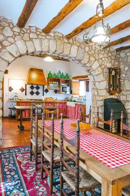 a kitchen and dining room with a stone wall at Masia Pou de la Vinya in Sitges