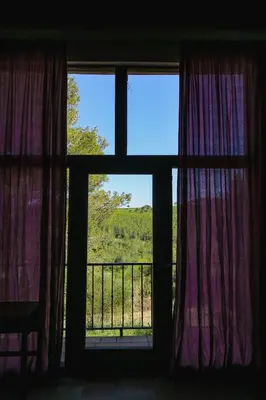 a room with two windows with purple curtains and a balcony at Masia Pou de la Vinya in Sitges