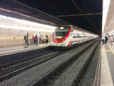 a train pulling into a train station with people on the platform at Spacious Duplex in Barcelona with outdoor terrace - 180 m² in Barcelona