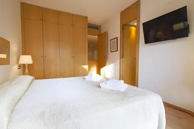 a bedroom with a white bed with a flat screen tv at Spacious Duplex in Barcelona with outdoor terrace - 180 m² in Barcelona