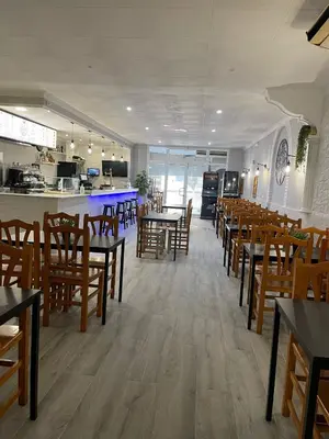 a restaurant with wooden tables and chairs and a kitchen at Hostal Restaurante Avenida de Madrid in Terrassa