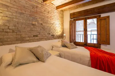 a bedroom with two beds and a brick wall at Happy People Ramblas Harbour Apartments in Barcelona