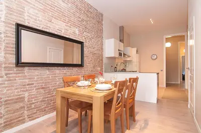 a dining room with a wooden table and a brick wall at Weflating Ramblas in Barcelona