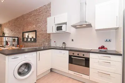 a kitchen with white cabinets and a washer and dryer at Weflating Ramblas in Barcelona