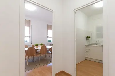 a kitchen and dining room with white walls and a mirror at Weflating Ramblas in Barcelona