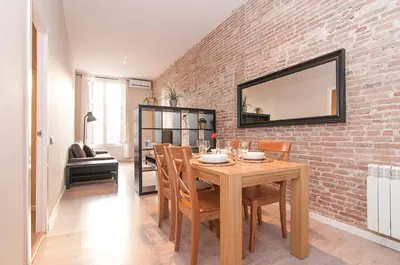 a dining room with a wooden table and a brick wall at Weflating Ramblas in Barcelona