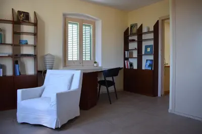 a living room with a white chair and a desk at Casa Le Bouganville in Sant Vicenç de Montalt