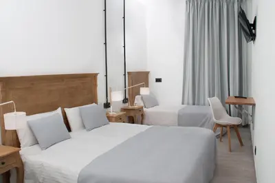a hotel room with two beds and a chair at Hostal Portofino in Arenys de Mar