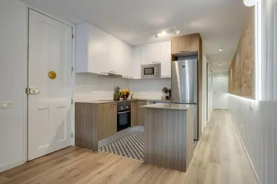 a kitchen with white cabinets and a stainless steel refrigerator at LucasLand Apartments Barcelona in Barcelona