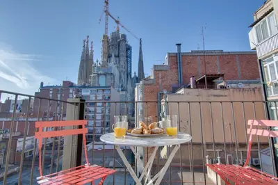 a table on a balcony with two chairs and orange juice at LucasLand Apartments Barcelona in Barcelona