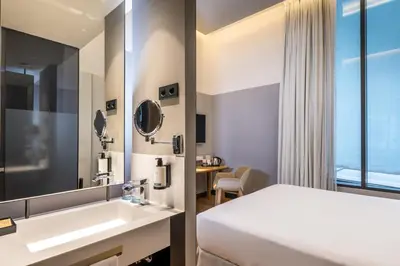a hotel room with a bed and a sink and a mirror at Occidental Diagonal 414 in Barcelona
