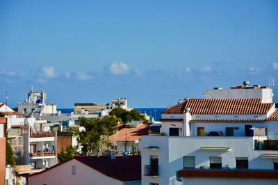 a group of buildings with the ocean in the background at Benito Apartment by Hello Homes Sitges in Sitges