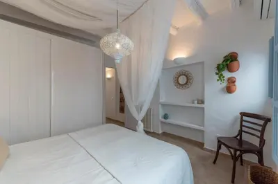 a bedroom with a white bed and a chair at Casa Azul by Hello Homes Sitges in Sitges