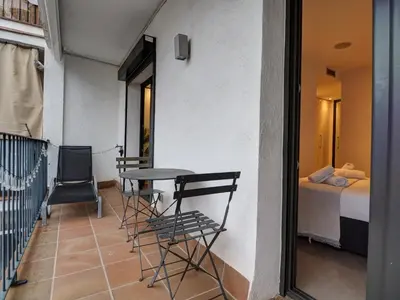 a balcony with a table and chairs and a bed at Chic by Hello Homes Sitges in Sitges