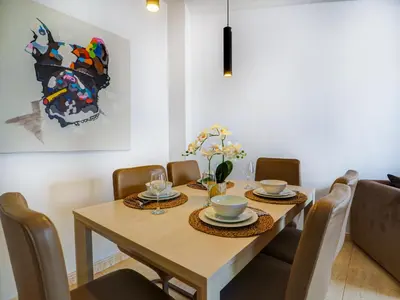 a dining room with a table with chairs and a painting at Sunlight by Hello Homes Sitges in Sitges