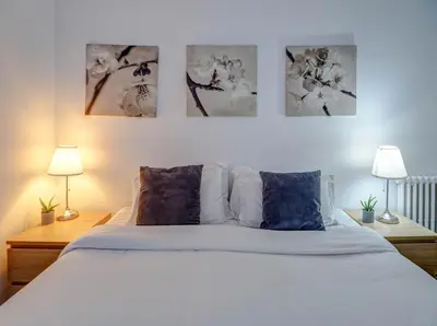 a bedroom with a white bed with three pictures on the wall at Soleil by Hello Homes Sitges in Sitges