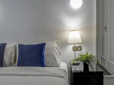 a bedroom with a bed with a blue pillow and a lamp at Soleil by Hello Homes Sitges in Sitges