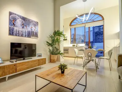 a living room with a large television and a table at En Vogue by Hello Homes Sitges in Sitges