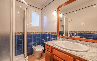 a bathroom with a sink and a toilet and a mirror at Gorgeous Home In Sant Cebrià De Vallalt in San Cipriano de Vallalta