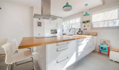 a kitchen with white cabinets and a wooden counter top at Magnificent apartment close to the beach in Barcelona