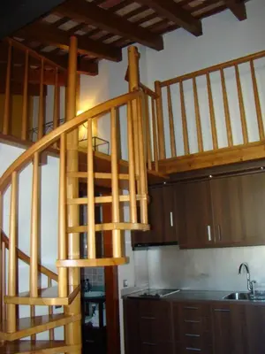 a wooden spiral staircase in a kitchen with a sink at Can Vilafort in Collsuspina