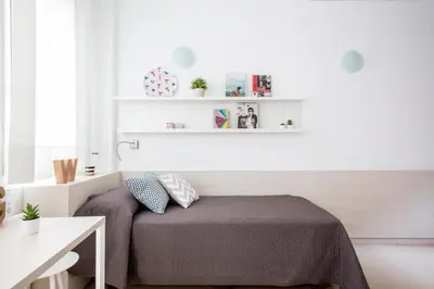 a bedroom with a bed and shelves on the wall at Residencia Universitaria Resa Francesc Giralt i Serrà in Terrassa