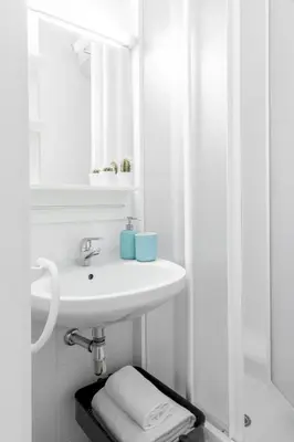 a white bathroom with a sink and a mirror at Residencia Universitaria Resa Francesc Giralt i Serrà in Terrassa