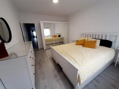 a white bedroom with a bed and a mirror at Nur Apartment in Terrassa