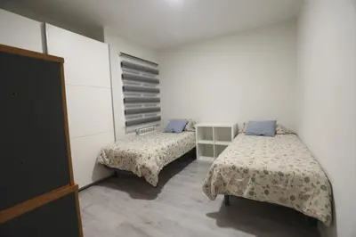 two beds in a room with white walls and blue pillows at Nur Apartment in Terrassa