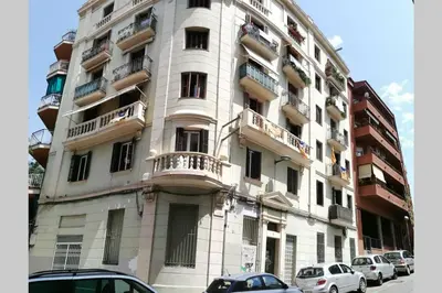 a tall building with cars parked in front of it at Chopin Magic Fountain in Barcelona