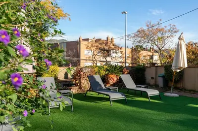 a patio with chairs and an umbrella and some flowers at TOWANDA HOUSE in Sant Just Desvern