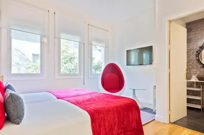 a bedroom with a bed with a red chair at Villa Victoria Barcelona in Barcelona