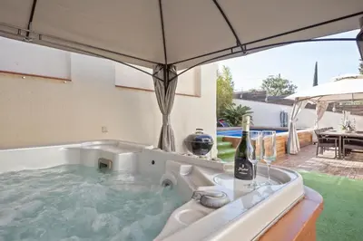 a hot tub with a bottle of wine and an umbrella at Villa Victoria Barcelona in Barcelona