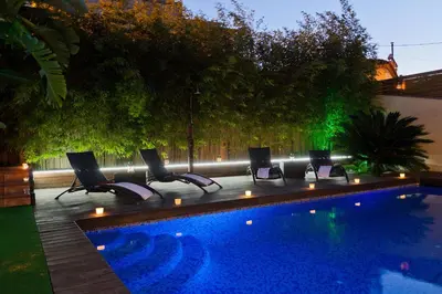 a swimming pool with chairs and lights next to it at Villa Victoria Barcelona in Barcelona
