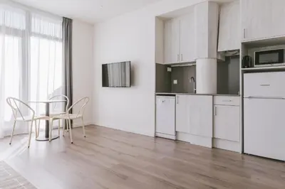 a kitchen with white cabinets and a table and chairs at CIM Aparthotel in Sant Cugat del Vallès