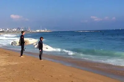 two people standing on the beach with a surfboard at Easystaybcn2 in Barcelona