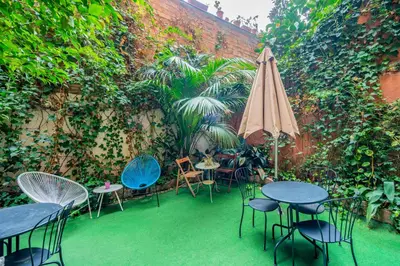 a patio with tables and chairs and an umbrella at Casa Barcelo Hostel Barcelona in Barcelona