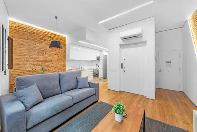 a living room with a blue couch and a brick wall at Sant Pau Ramblas Apartments Serennia in Barcelona