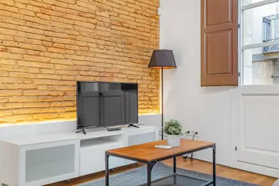 a living room with a tv and a brick wall at Sant Pau Ramblas Apartments Serennia in Barcelona