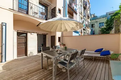 a wooden deck with a table and an umbrella at Sant Pau Ramblas Apartments Serennia in Barcelona
