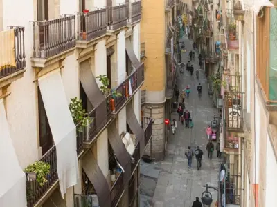 a group of people walking down a street between buildings at Sant Pau Ramblas Apartments Serennia in Barcelona