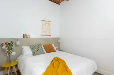 a bedroom with a white bed with a yellow blanket on it at Casa Cosi - Putxet 4 in Barcelona