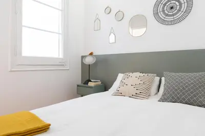 a white bedroom with a white bed and a window at Casa Cosi - Putxet 4 in Barcelona