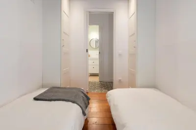 two beds in a room with white walls and wooden floors at Casa Cosi - Putxet 4 in Barcelona