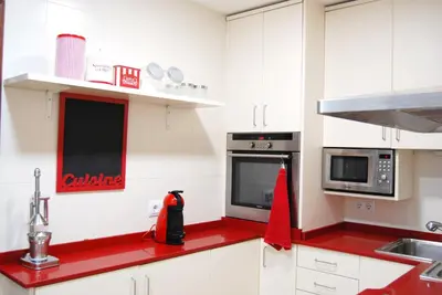 a kitchen with white cabinets and a red counter top at Panier en Osier · Panier en Osier · Charming apartment w/private terrace 2min from sea in Vilassar de Mar