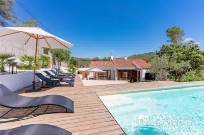 a pool with chairs and an umbrella next to a house at Villa Falco is a beautiful single storey holiday villa with private pool in Viladellops