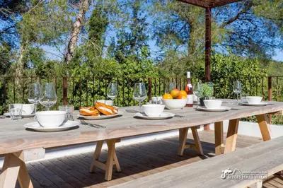 a wooden deck with a wooden table and chairs at Villa Falco is a beautiful single storey holiday villa with private pool in Viladellops