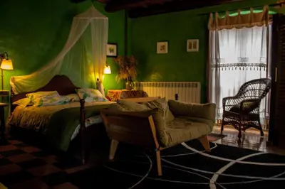 a bedroom with green walls and a bed and a chair at El Folló Turisme Rural in Tagamanent